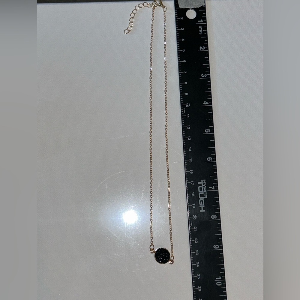 gold necklace featuring a striking black crystal